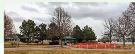 Rolling Hills Park Playground on a rainy day. The playground has been removed for construction and the area is now surrounded by orange cones and gate for safety
