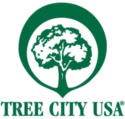 Tree city USA logo is green with a large circle around a bushy tree and the words "Tree City USA"